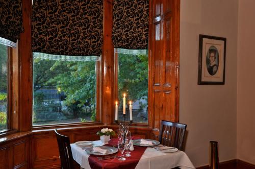 a dining room with a table and two windows at Die Kliphuis in Standerton