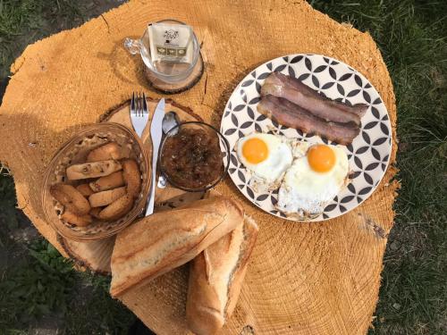 - une table avec petit-déjeuner composé d'œufs, de saucisses et de pain dans l'établissement camping l'agrottu au cœur de la corse, à Santa-Lucia-di-Mercurio