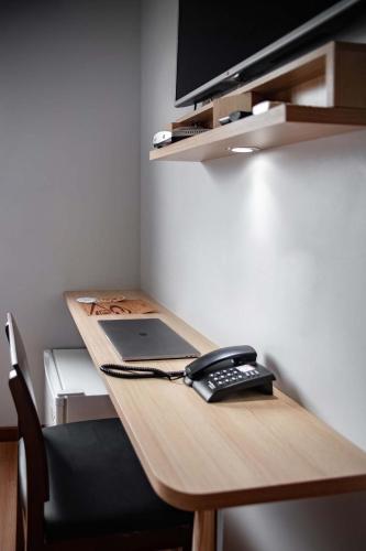 a desk with a laptop and a phone on it at Blu Terrace Hotel in Blumenau