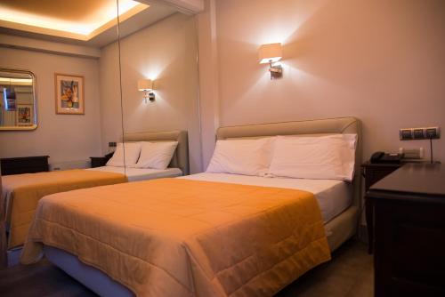 um quarto de hotel com duas camas com lençóis laranja em Hotel Maroussi em Atenas