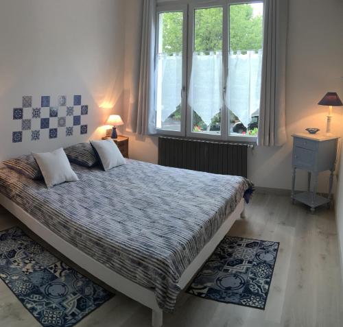 a bedroom with a bed and two windows at Les Citadines in Amboise