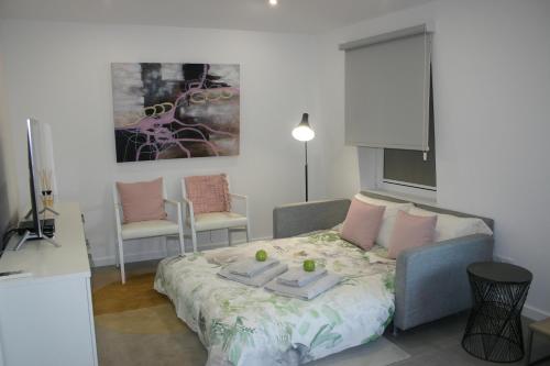 a bedroom with a bed and two chairs and a painting at APARTAMENTO MAR WITH PARKINg in Sesimbra