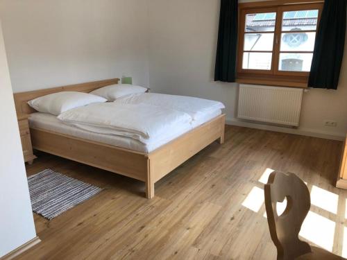 una camera da letto con un letto con lenzuola bianche e una finestra di Landgasthaus zum Altwirt Reichersbeuern a Reichersbeuern