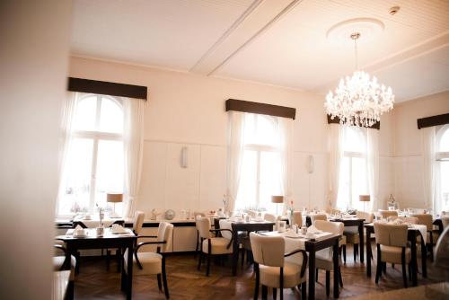 a dining room with tables and chairs and a chandelier at Heerens Hotel in Emden