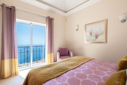 a bedroom with a bed and a large window at Designed Villa Palheiro Village by HR Madeira in Funchal