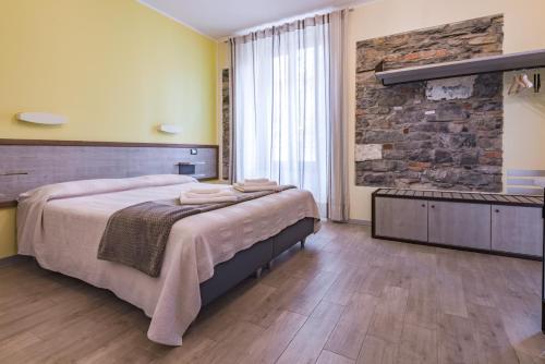 sypialnia z dużym łóżkiem i kamienną ścianą w obiekcie VIA VENEZIA 76 w mieście La Spezia