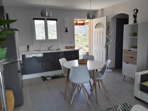 cocina con mesa blanca y sillas blancas en Residence Sejoina, en Calcatoggio