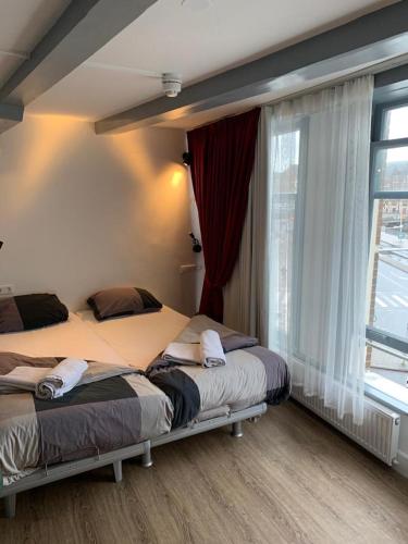 a bedroom with two beds and a large window at Hotel Restaurant Old Bridge in Amsterdam