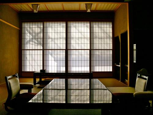 a room with a glass table and chairs and windows at Takanosukan in Sekikawa