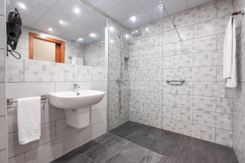 y baño blanco con lavabo y ducha. en Hotel Concorde, en Las Palmas de Gran Canaria