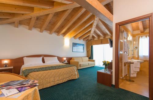 una camera d'albergo con due letti e un soggiorno di Hotel Capri Bardolino 3S a Bardolino