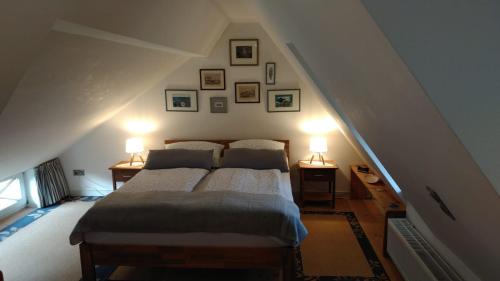 a bedroom with a bed with two lamps and pictures on the wall at Das Rosenhaus in Utersum