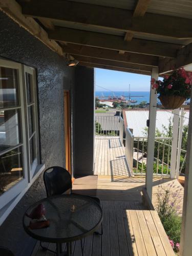 a table and chairs on a porch with a view of the ocean at 58 Pioneer - Retro Studio Unit in New Plymouth