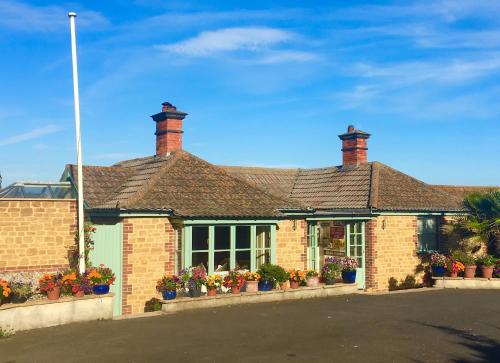 a brick house with potted plants in front of it at Heatherbell Cottage Guest Accommodation in West Bay