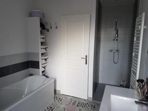 La salle de bains est pourvue d'une baignoire blanche et d'une porte blanche. dans l'établissement Charmante maison de ville, au Mans