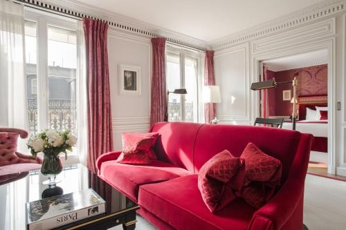 a living room with a red couch and a bedroom at La Réserve Paris Hotel & Spa in Paris