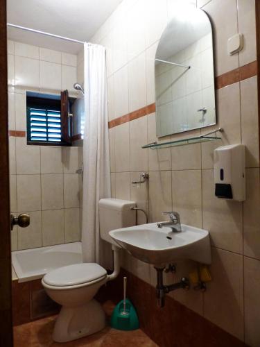 a bathroom with a toilet and a sink and a mirror at Apartmani Villa Jasminka in Podgora