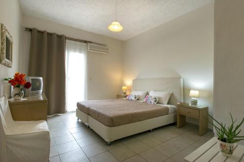 a bedroom with a bed and a tv and a couch at KORMORANOS BEACH in Acharavi