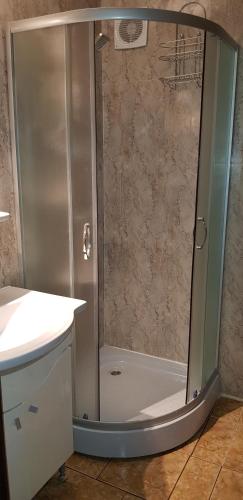 a shower with a glass door next to a sink at Apartament Belvedere in Olimp