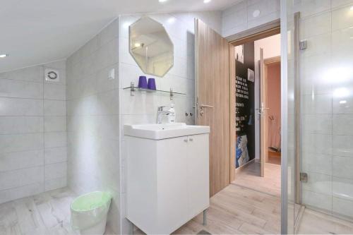 a white bathroom with a sink and a shower at Apartmani Natali in Zadar