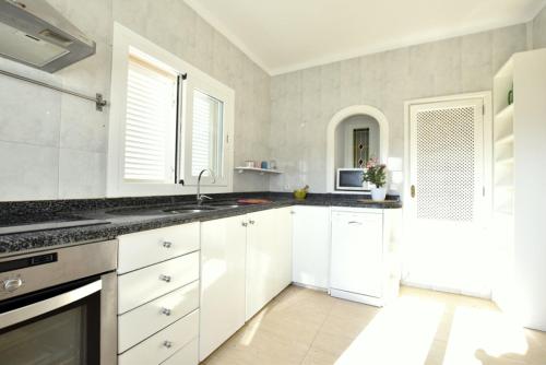 una cocina blanca con armarios blancos y fregadero en Paris en Alcúdia