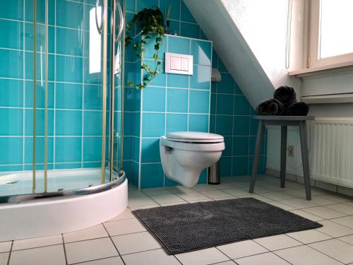 a bathroom with a toilet and a blue tiled wall at Odyssee in Zandvoort