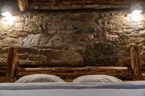 two beds in a room with a stone wall at Скендерова Къща Къщичка Алиса in Leshten
