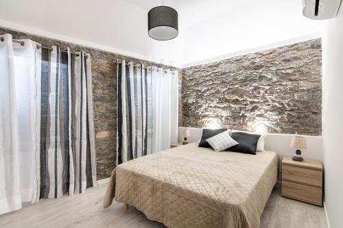 1 dormitorio con cama y pared de piedra en A CASINHA en Câmara de Lobos