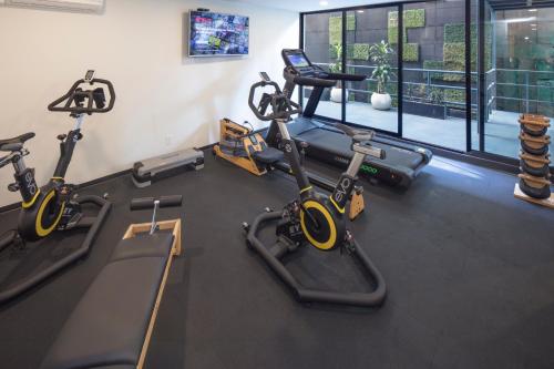 a gym with two treadmills and two exercise bikes at FlowSuites Condesa - Adults Only in Mexico City