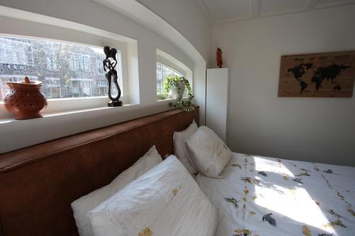 a bedroom with a bed with white pillows and a window at Het prinsentuintje in Leeuwarden