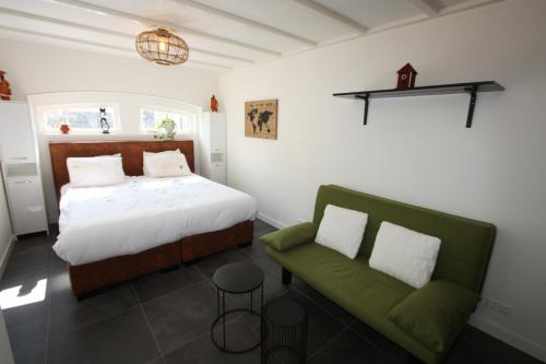 een slaapkamer met een bed en een groene bank bij Het prinsentuintje in Leeuwarden