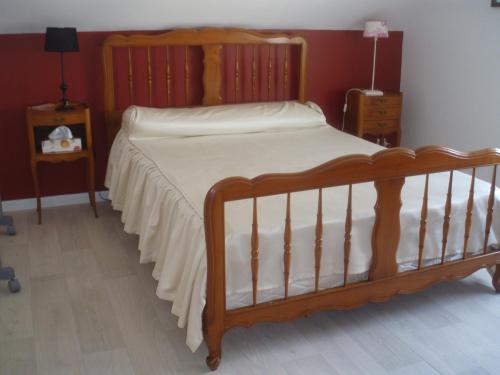- une chambre avec un lit en bois et des draps blancs dans l'établissement Chambre d'Hôte de la Belle Jardinière, à Chagny