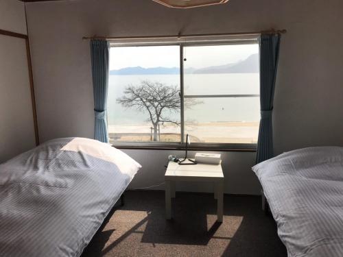 高松市にある女木島ゲストハウス&カフェMeginoのベッド2台、木の窓が備わる客室です。