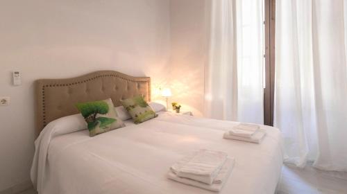 a bedroom with a white bed with towels on it at ALOJAMIENTO EN SEVILLA-TRIANA in Seville
