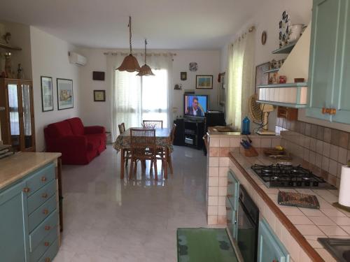 a kitchen and living room with a red couch at Villetta immersa nel verde ma vicina al mare in Lascari