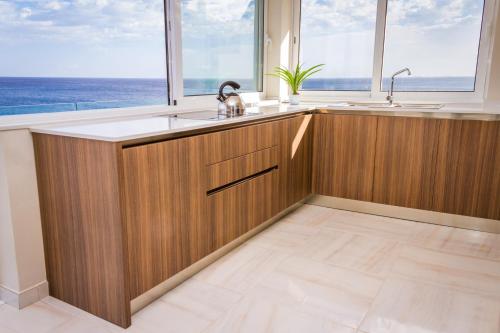 eine Küche mit Holzschränken und Meerblick in der Unterkunft Lux Apartments in Xgħajra