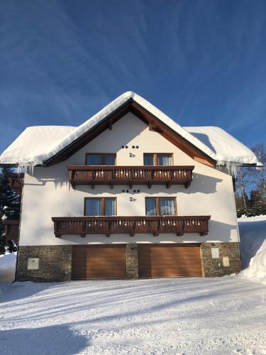 a snow covered house with a balcony on top of it at pension George in Špindlerův Mlýn