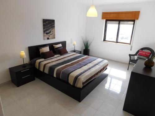 een slaapkamer met een bed, 2 tafels en een raam bij Tropical Rocha Residence in Portimão