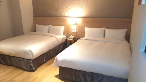 a hotel room with two beds and a telephone at Lucky Apple Hotel in Taipei