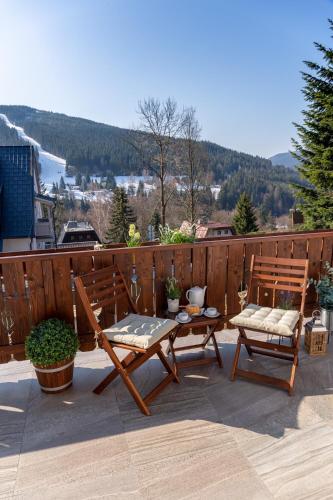 a patio with two benches and a table on a balcony at pension George in Špindlerův Mlýn