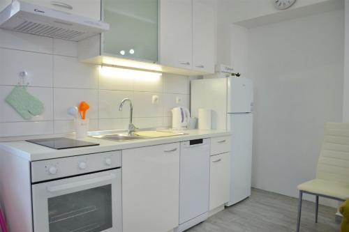 a white kitchen with a sink and a refrigerator at Downtown Sweet Studio in Novalja