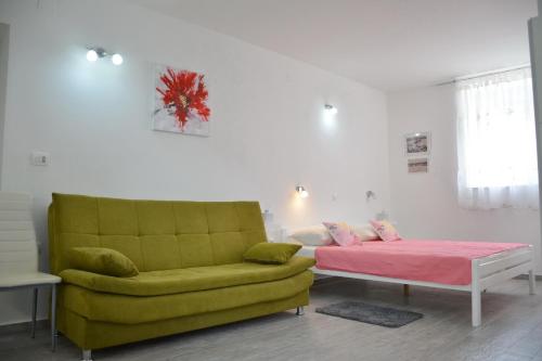 a living room with a bed and a yellow couch at Downtown Sweet Studio in Novalja