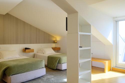 um quarto com duas camas e uma estante de livros em Hotel Laranjeira em Viana do Castelo