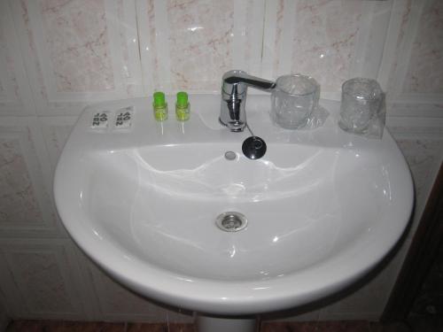 - un lavabo blanc avec 2 bouteilles et des verres dans l'établissement Hostal Alvaro I, à Alborea