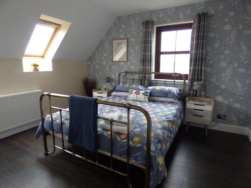 a bedroom with a bed with a blue comforter at Ornum Self Catering Cottage in Eabost