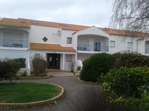 une maison blanche avec des balcons bleus et une allée. dans l'établissement les genets, à Bretignolles-sur-Mer