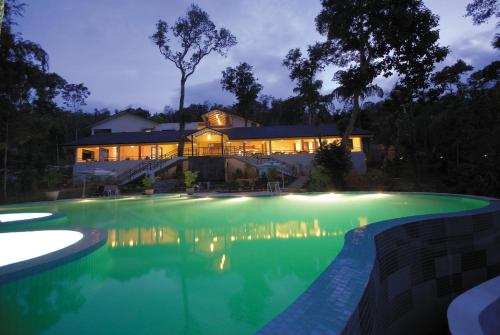 una casa con piscina por la noche en The Windflower Resort & Spa, Coorg, en Suntikoppa