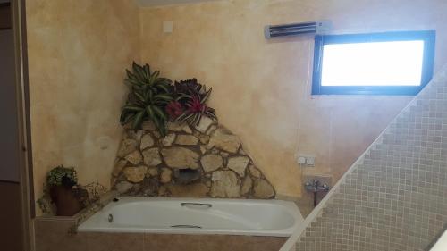 y baño con bañera y pared de piedra. en Finca El Manzano, en Cortegana