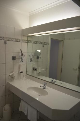 a bathroom with a sink and a large mirror at Hotel Zur Post in Neubruchhausen