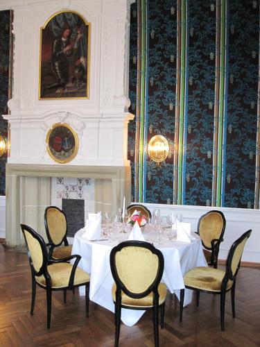 a dining room with a table and chairs and a fireplace at Hotel Schloss Wilkinghege in Münster